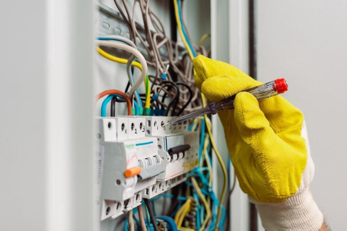 Électricien vérifiant un tableau électrique avec un tournevis testeur